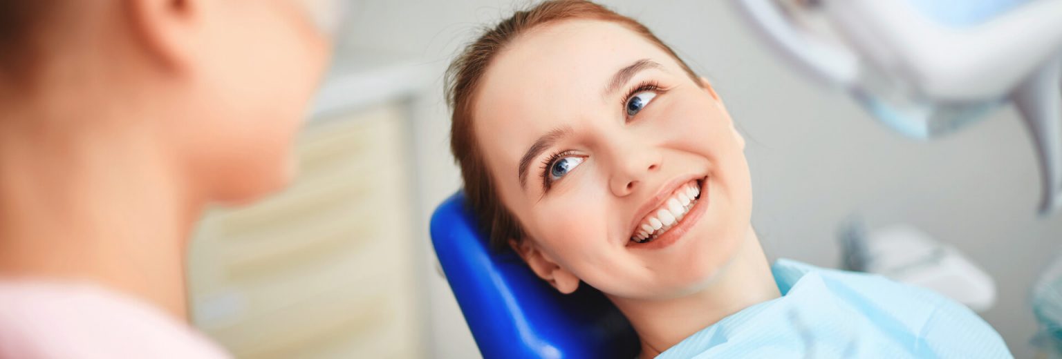 Happy young lady sitting on a dental chair